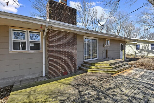 back of house featuring a wooden deck, brick siding, and a chimney