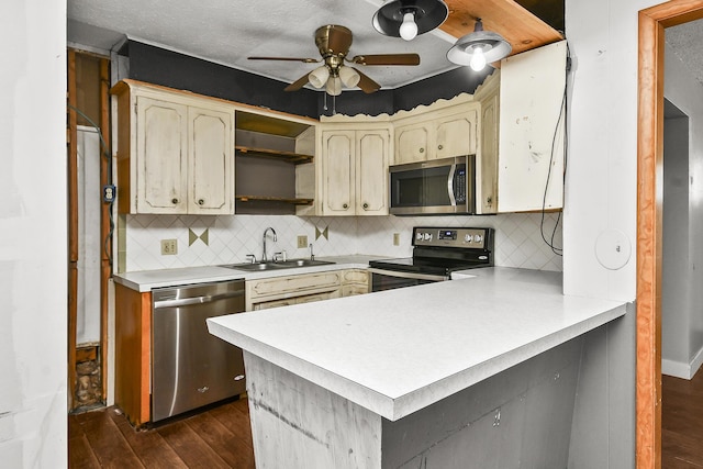 kitchen featuring dark wood-type flooring, a sink, stainless steel appliances, a peninsula, and light countertops