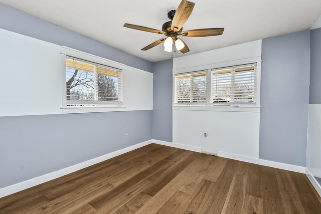 empty room with a ceiling fan, wood finished floors, baseboards, and a wealth of natural light