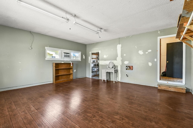 unfurnished living room with baseboards, a textured ceiling, and wood finished floors