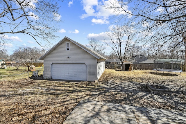 detached garage with a trampoline and fence