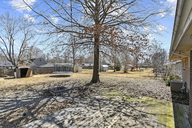 view of yard with an outbuilding, a trampoline, a fenced backyard, and a shed