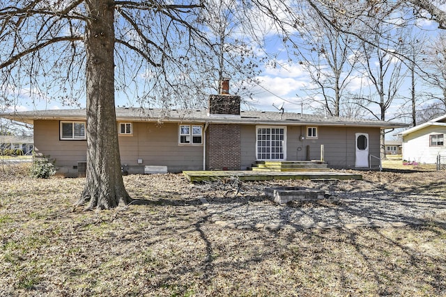 back of property with crawl space and a chimney