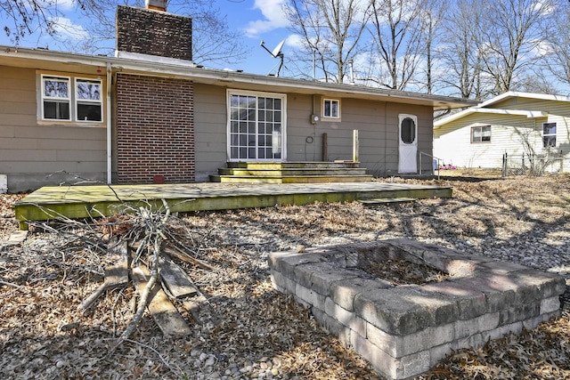 rear view of house with brick siding, an outdoor fire pit, entry steps, and a chimney