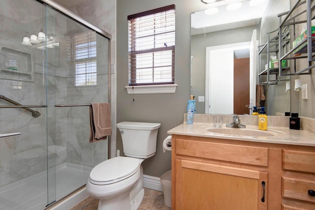 bathroom featuring vanity, a shower stall, toilet, and baseboards