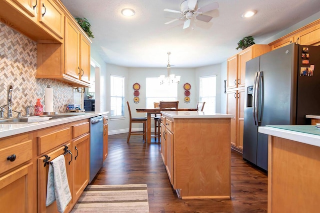 kitchen featuring a sink, stainless steel appliances, light countertops, tasteful backsplash, and a center island