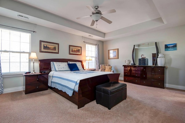 bedroom with visible vents, multiple windows, and a tray ceiling