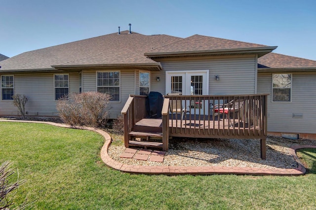 back of house with a wooden deck, a lawn, and roof with shingles