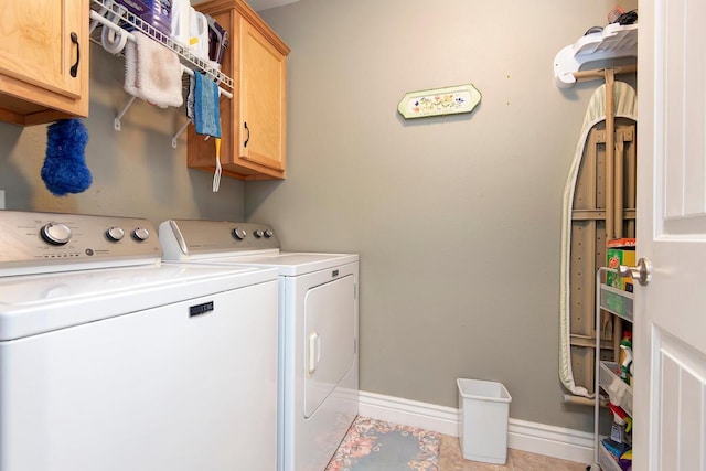 clothes washing area featuring baseboards, cabinet space, and washer and clothes dryer