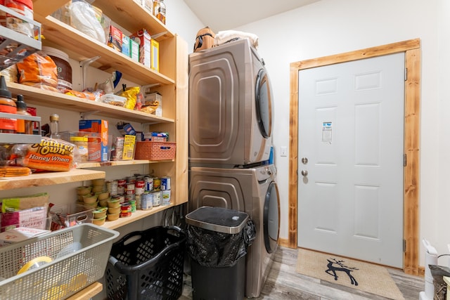 laundry area featuring laundry area, light wood-style flooring, and stacked washer / drying machine