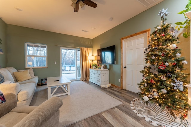 living room with visible vents, wood finished floors, and a ceiling fan