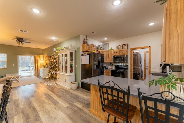 kitchen featuring visible vents, black appliances, a sink, light wood-style floors, and a peninsula