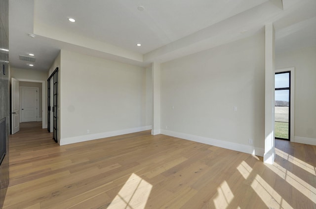 empty room with light wood finished floors, visible vents, recessed lighting, and baseboards