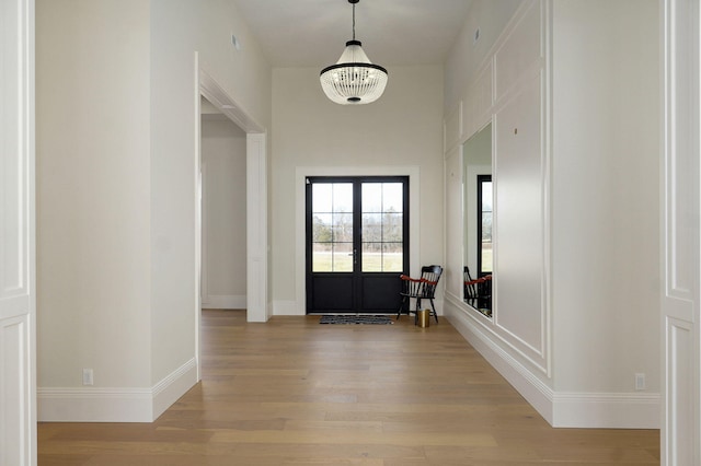 foyer entrance with french doors, baseboards, and light wood finished floors