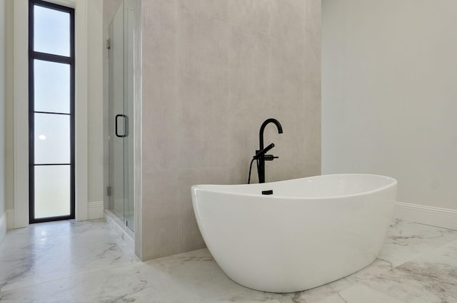 full bath featuring a freestanding tub, a healthy amount of sunlight, marble finish floor, and a stall shower