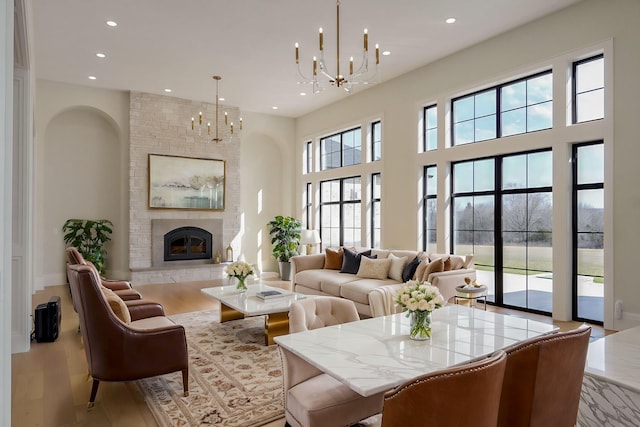 living area featuring a notable chandelier, recessed lighting, a large fireplace, and wood finished floors