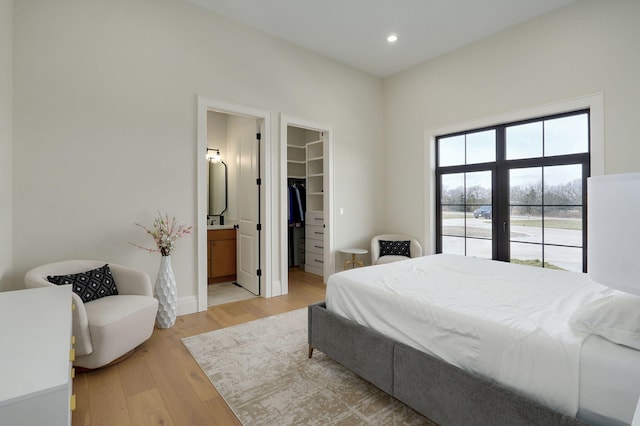 bedroom with a walk in closet, light wood-type flooring, recessed lighting, ensuite bathroom, and a closet