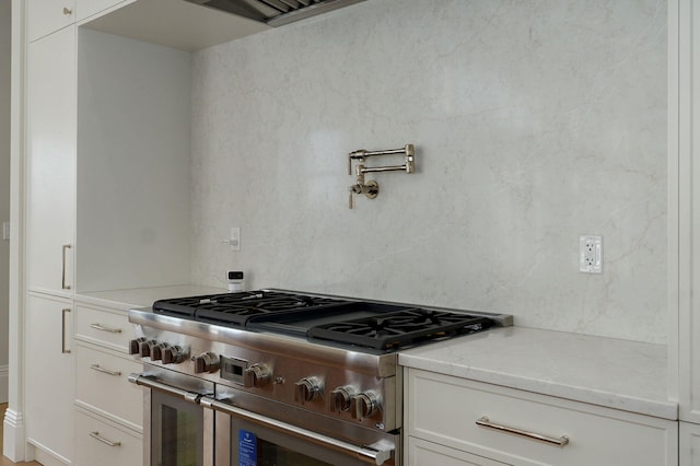 kitchen featuring light stone counters, double oven range, and white cabinetry