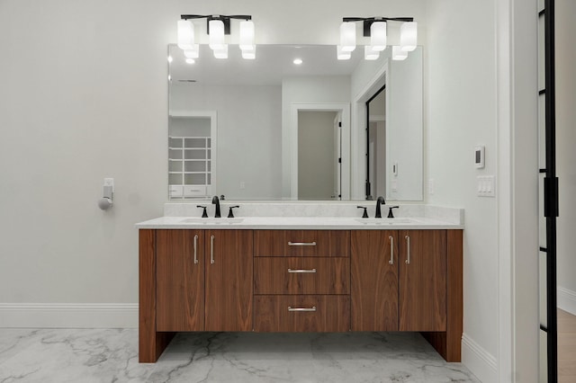 bathroom featuring a sink, baseboards, marble finish floor, and double vanity