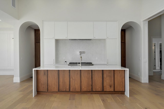 kitchen featuring arched walkways, light wood-style flooring, and light countertops