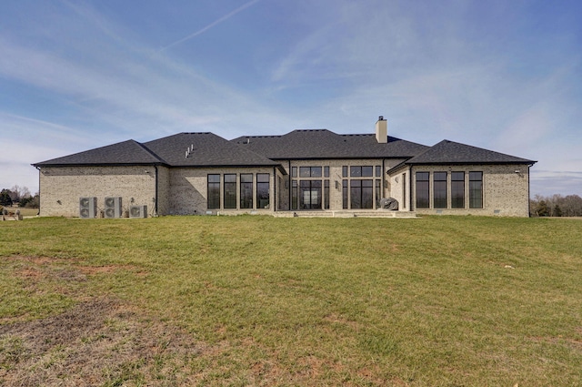 back of property with a yard, brick siding, and a chimney