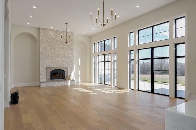 unfurnished living room featuring a notable chandelier, a fireplace, recessed lighting, and light wood finished floors