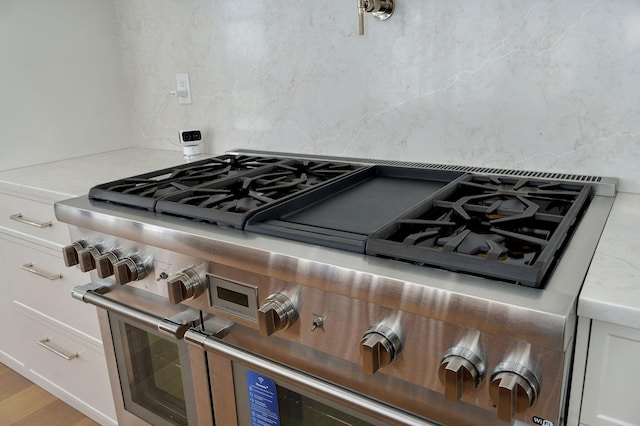 kitchen featuring double oven range, tasteful backsplash, white cabinets, and light countertops