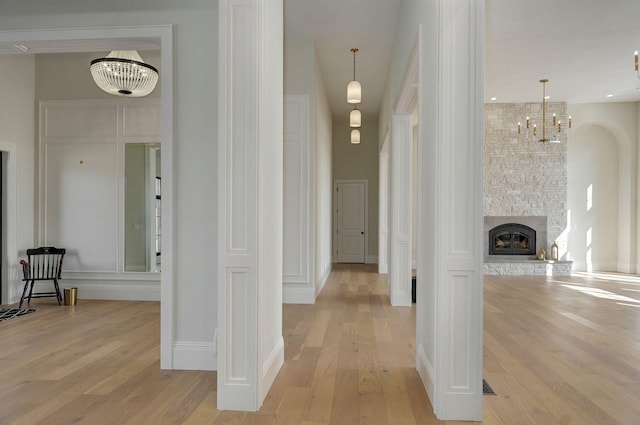 corridor with light wood finished floors, a notable chandelier, and a towering ceiling