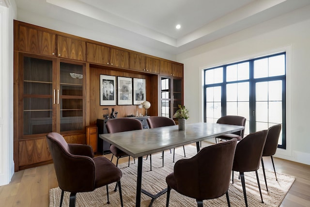 dining area featuring recessed lighting, light wood-style flooring, a raised ceiling, and baseboards