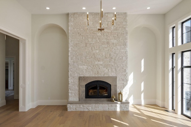 unfurnished living room with wood finished floors, recessed lighting, a fireplace, and baseboards