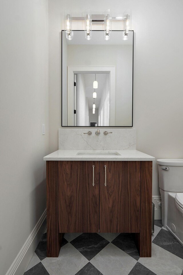 half bathroom with decorative backsplash, toilet, vanity, and baseboards