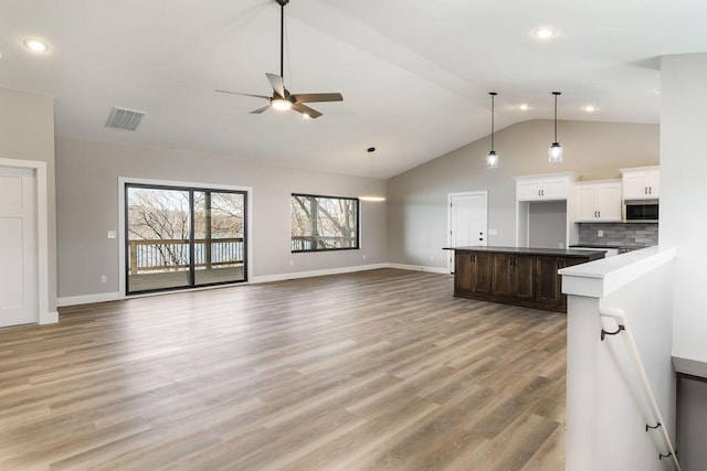 kitchen with visible vents, open floor plan, decorative backsplash, and stainless steel microwave