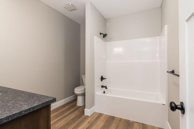 bathroom featuring vanity, wood finished floors, baseboards, shower / bath combination, and toilet