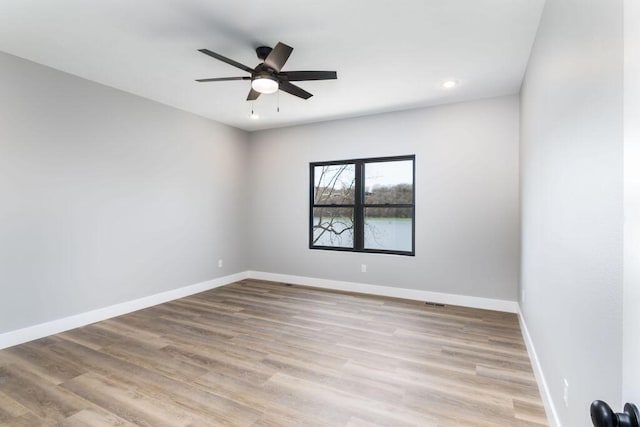 empty room with a ceiling fan, recessed lighting, wood finished floors, and baseboards