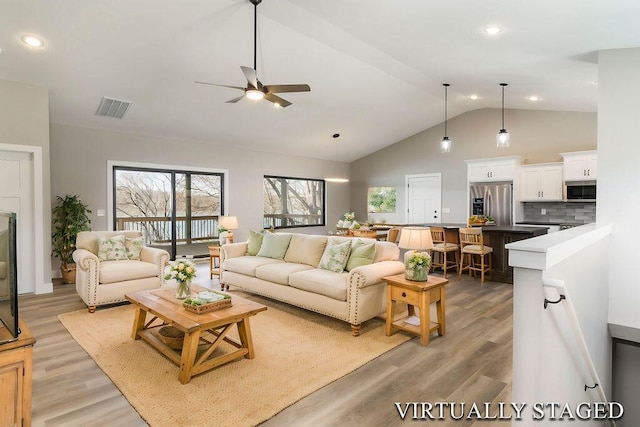 living room featuring visible vents, light wood-style floors, high vaulted ceiling, and a ceiling fan