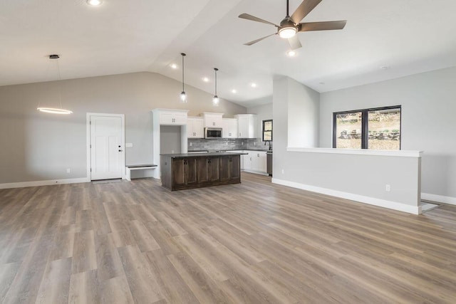 kitchen featuring white cabinetry, open floor plan, backsplash, and stainless steel appliances