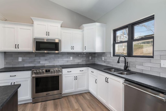 kitchen with dark wood-type flooring, a sink, dark countertops, appliances with stainless steel finishes, and white cabinets