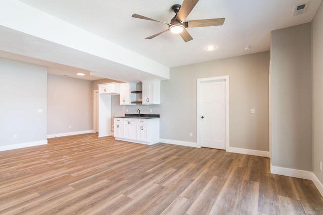 unfurnished living room featuring a ceiling fan, light wood-style flooring, baseboards, and visible vents