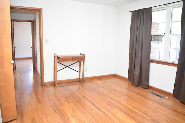 empty room featuring light wood-style flooring, plenty of natural light, and baseboards