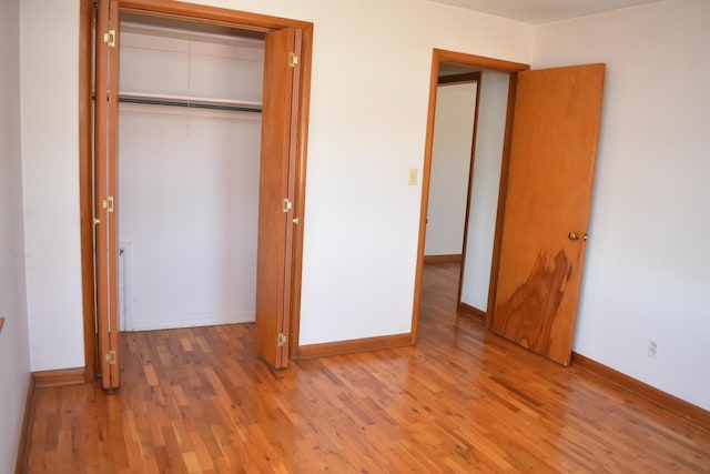 unfurnished bedroom featuring a closet, baseboards, and wood finished floors