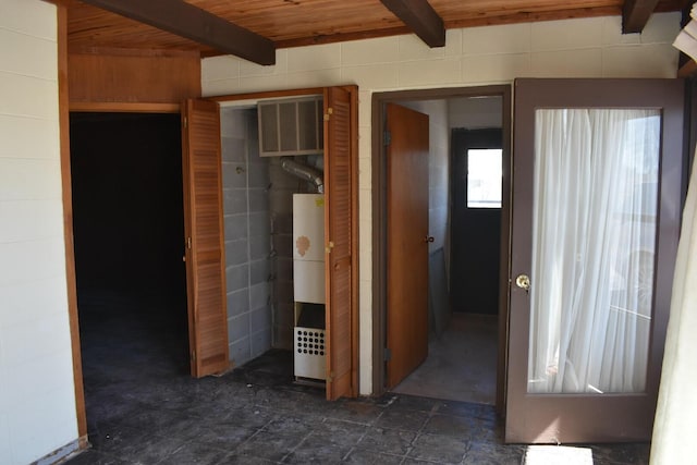 unfurnished bedroom with beam ceiling, wood ceiling, and stone finish floor