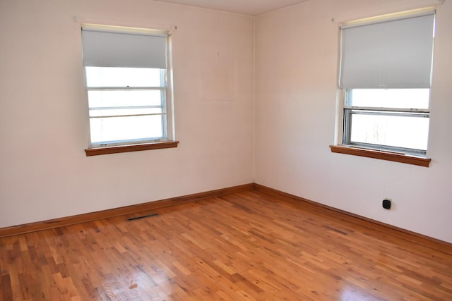 empty room with visible vents, baseboards, and wood finished floors