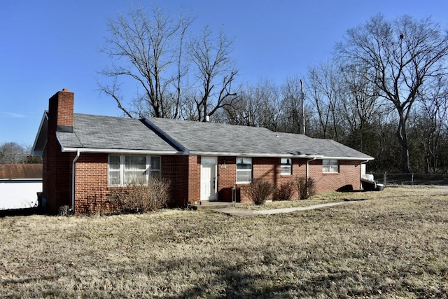 ranch-style home with brick siding, a chimney, and fence