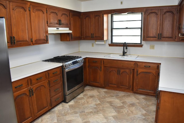 kitchen with under cabinet range hood, stainless steel appliances, light countertops, and a sink