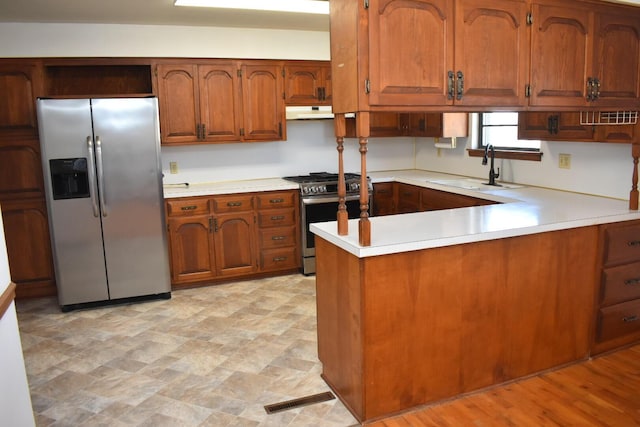 kitchen featuring a sink, light countertops, brown cabinetry, and stainless steel appliances