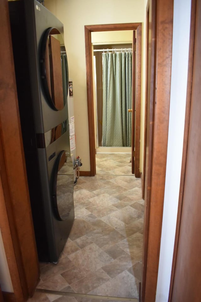 corridor featuring baseboards and stacked washer and clothes dryer