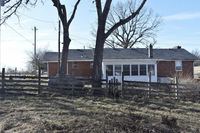 rear view of house featuring brick siding and a fenced front yard