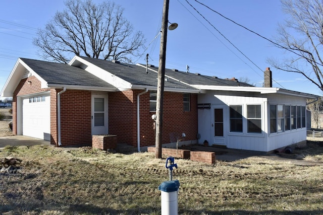 view of front of house with an attached garage, brick siding, and a chimney