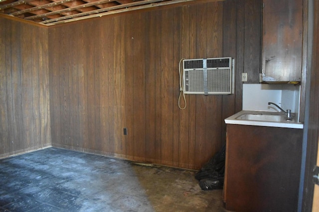 below grade area with a sink, an AC wall unit, and wood walls