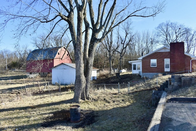 view of yard with a barn, an outdoor structure, and fence